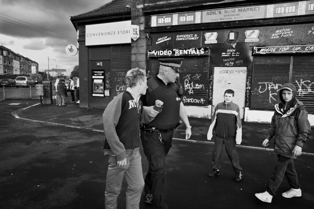 A sergeant in a police public order unit has a word with young boys causing trouble outside shop in Glasgow's East End