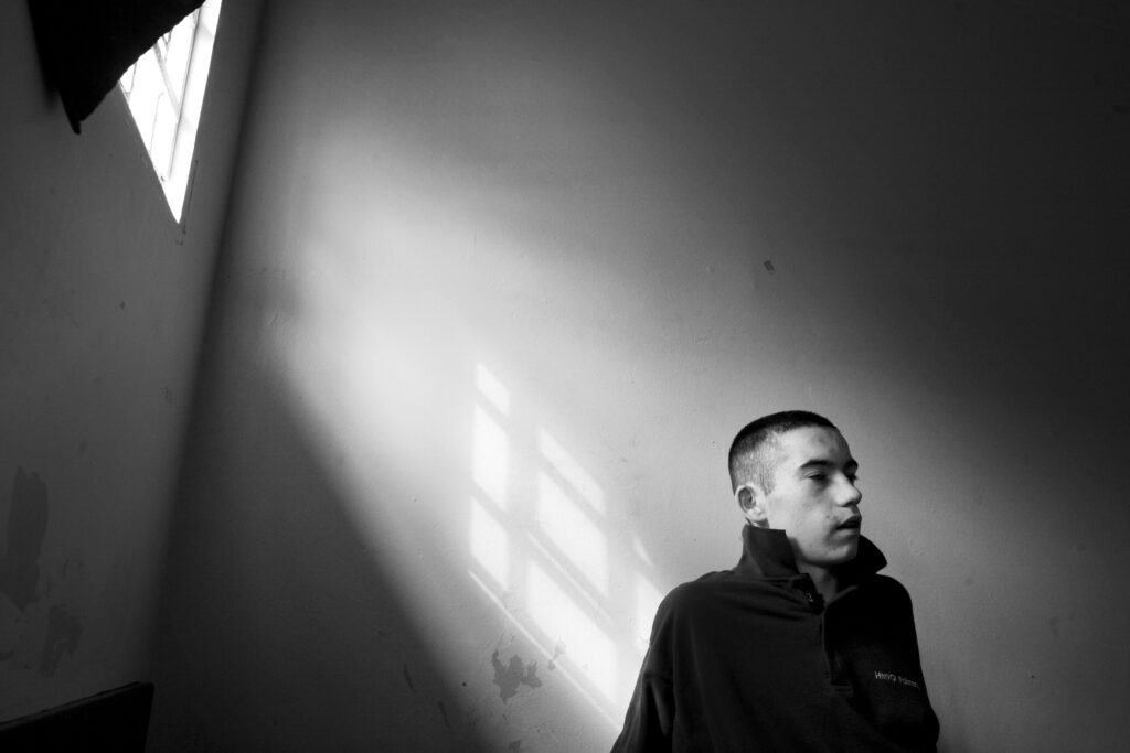 A young offender sentenced for knife offences sits under the shadow of his prison cell bars in Polmont Young Offenders Institution, Scotland
