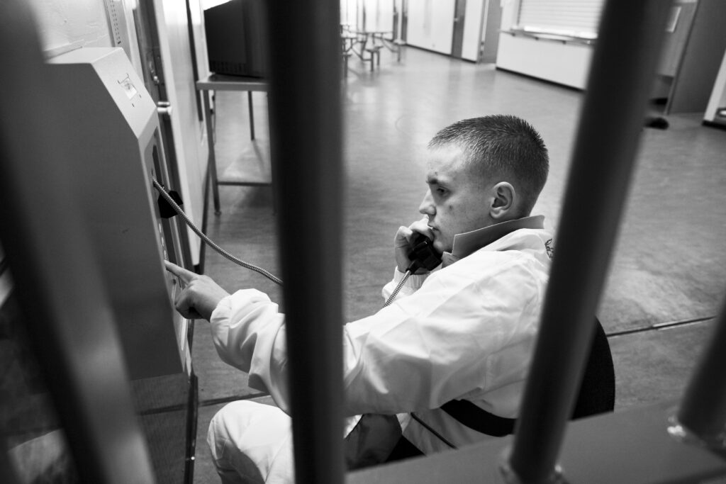 Seen through prison bars, a young man uses a payphone at Polmont Young Offenders Institution in Scotland.