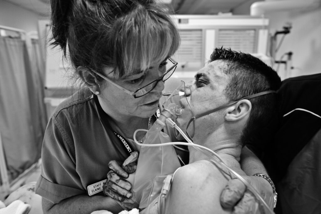 A nurse comforts a young man who has been stabbed several times. Glasgow Royal Hospital A&E, Glasgow Scotland